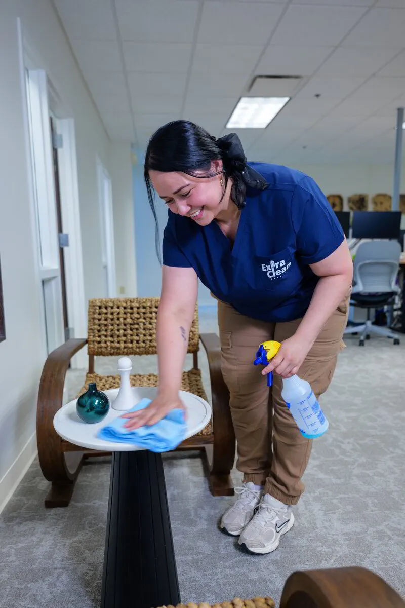 An ExtraClean team member wiping a table in an open office