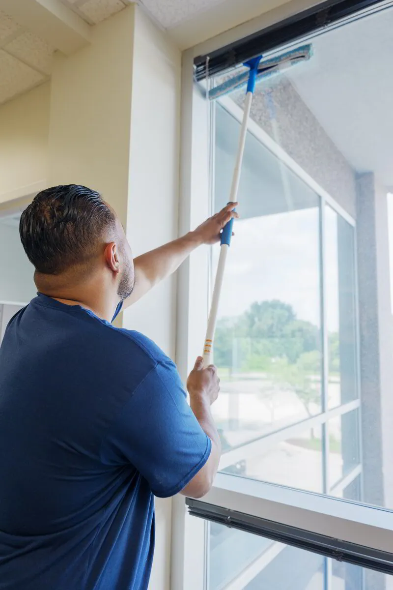 An ExtraClean team member washing a tall office window with an extension pole