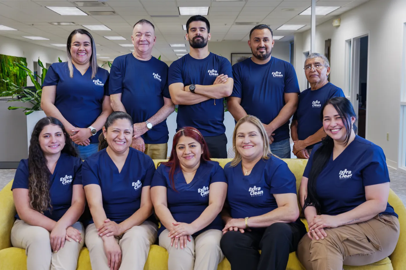 The ExtraClean team, about a dozen people in navy ExtraClean shirts, posing together in an office